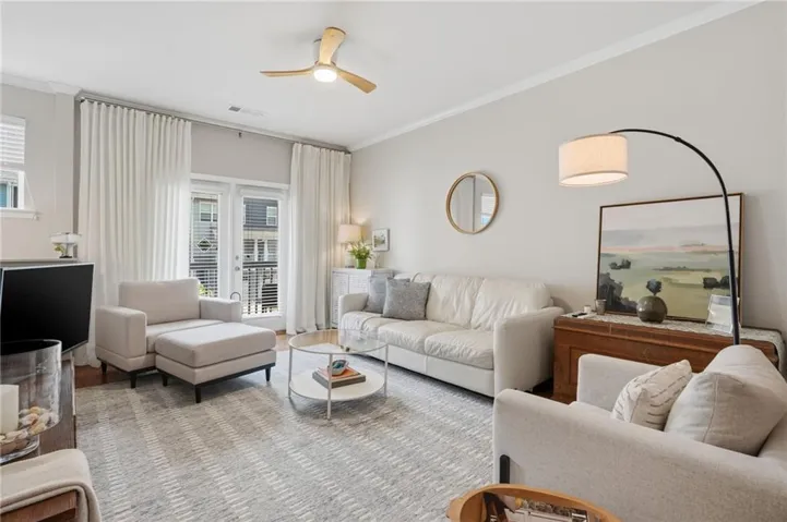 Crown molding, wood-finish flooring, ceiling fan with integrated lighting, double patio doors, and light-toned wall finishes