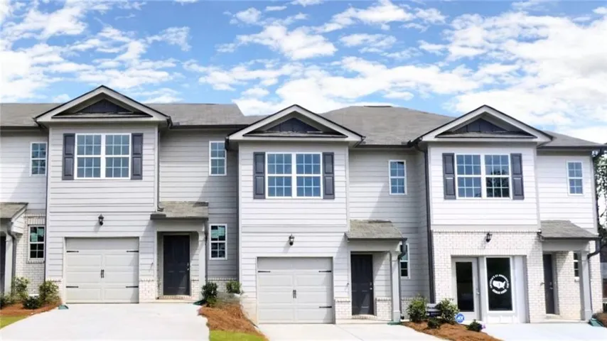 Modern townhome exterior featuring light gray siding, dark shutters, and a prominent gable roofline