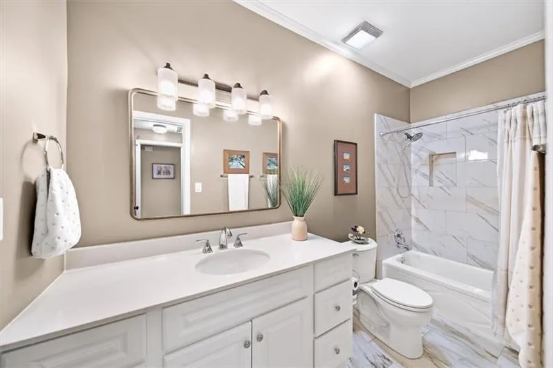 Bathroom featuring shower / tub combo with curtain, vanity, and crown molding