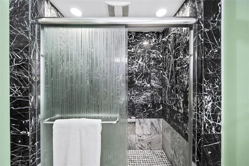 Full bath with a marble finish shower
