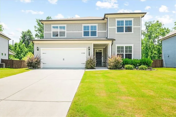 Two-story residence featuring a two-car garage, established landscaping, and a covered entry