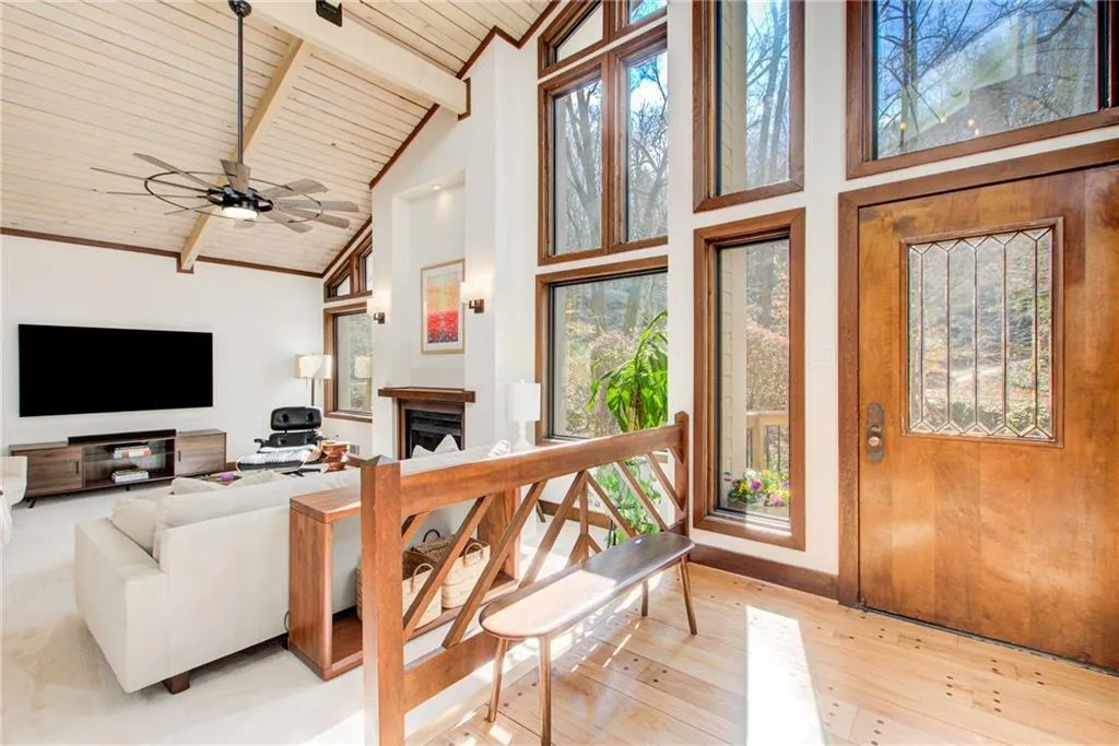 Family room featuring a fireplace, a high wood beamed ceiling, light wood-style floors, and ceiling fan