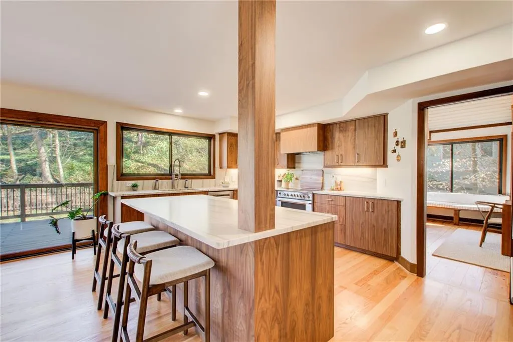 Kitchen with light wood-type flooring, healthy amount of natural light, a kitchen bar, recessed lighting, and wood finish cabinetry