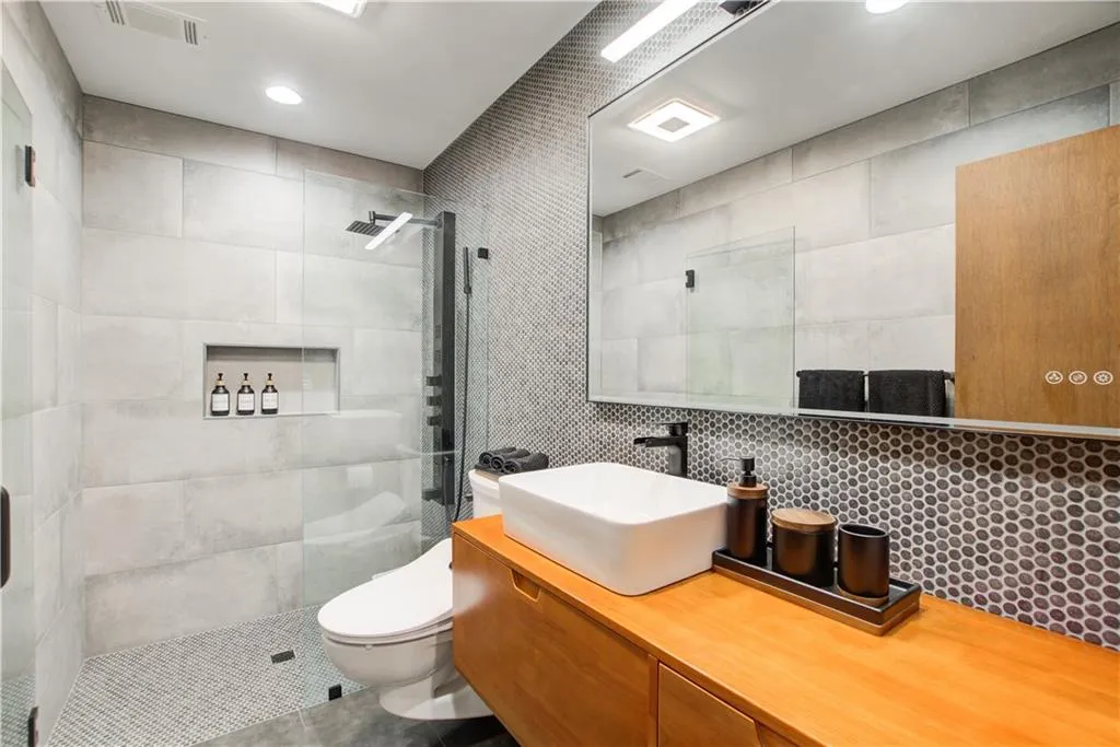 Bathroom with a shower stall, vanity, and tile walls