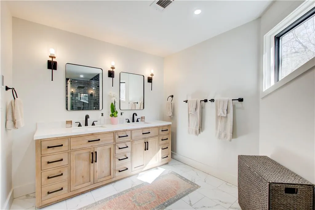 Full bath featuring double vanity, light marble finish flooring, and recessed lighting