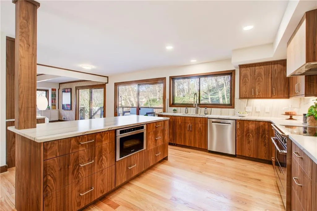 Kitchen featuring wood finish cabinetry, stainless steel appliances, a center island, modern cabinets, and light wood-style floors