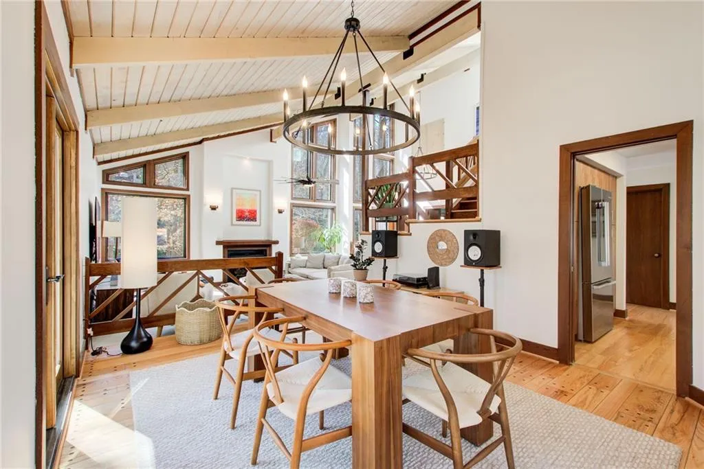Dining room featuring a fireplace, light wood-style floors, suspended lighting, vaulted ceiling, and a ceiling fan