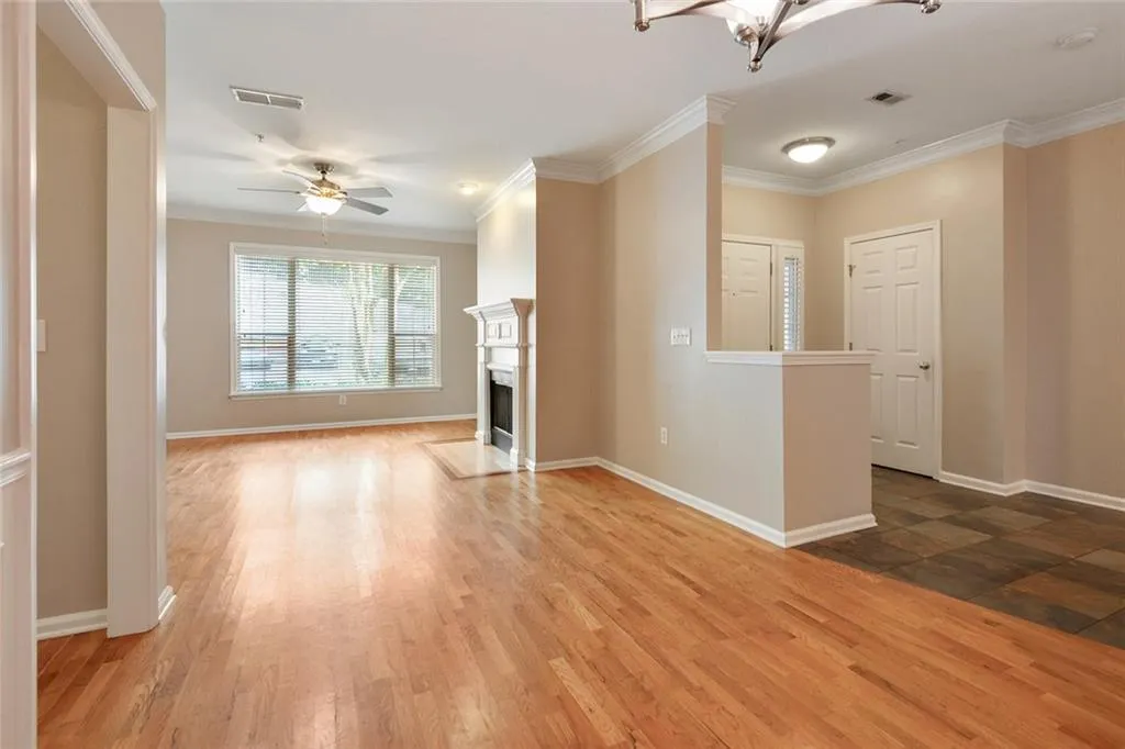 Unfurnished living room featuring ornamental molding, light wood-style floors, a high end fireplace, a ceiling fan, and a chandelier