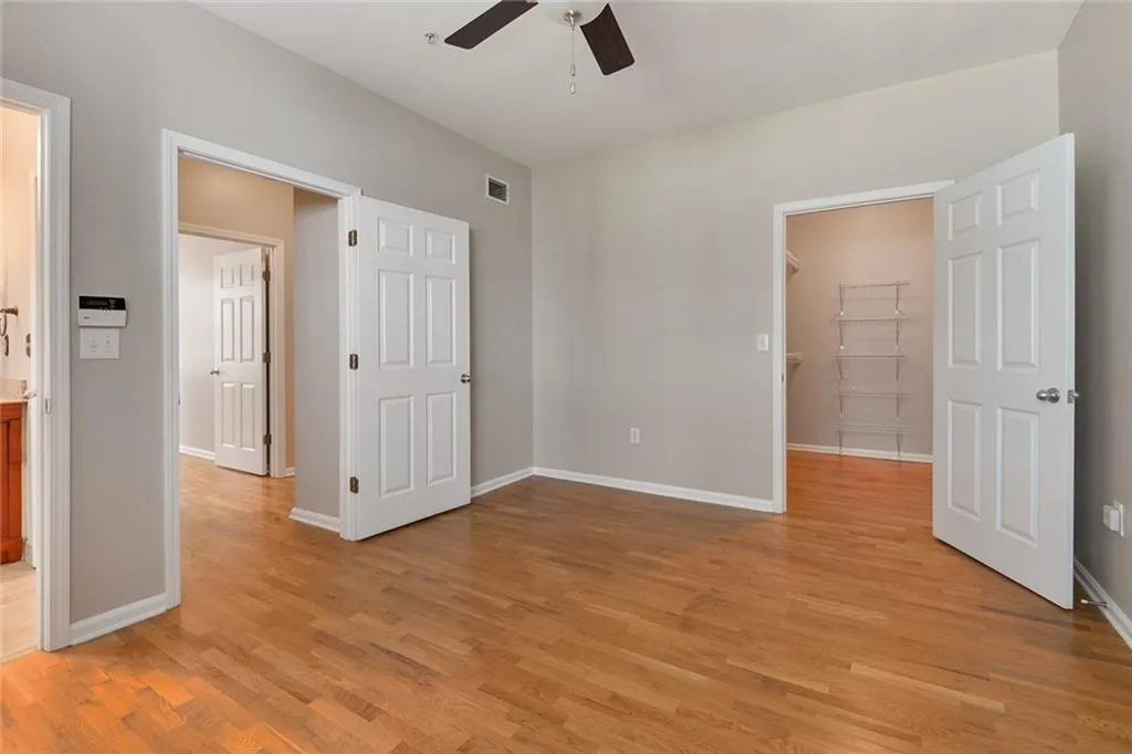 Unfurnished bedroom featuring light wood-type flooring, a spacious closet, and a ceiling fan