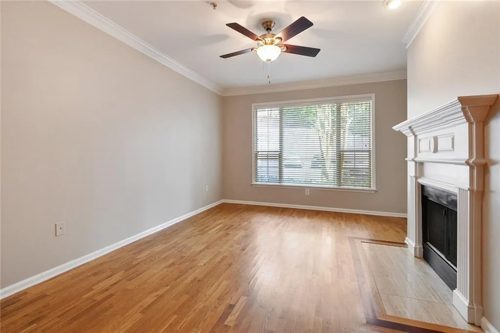 Unfurnished living room featuring crown molding, light wood-type flooring, a fireplace, and ceiling fan