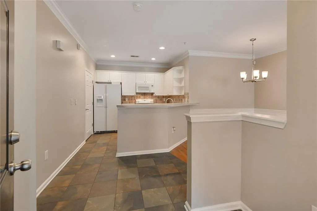Kitchen with tasteful backsplash, white appliances, crown molding, a peninsula, and white cabinets