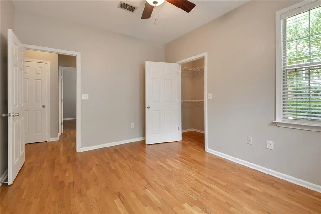 Unfurnished bedroom with light wood-style flooring, a spacious closet, and a ceiling fan