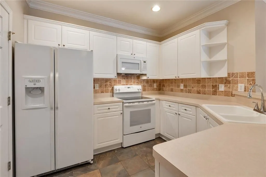 Kitchen featuring white appliances, ornamental molding, open shelves, white cabinetry, and backsplash