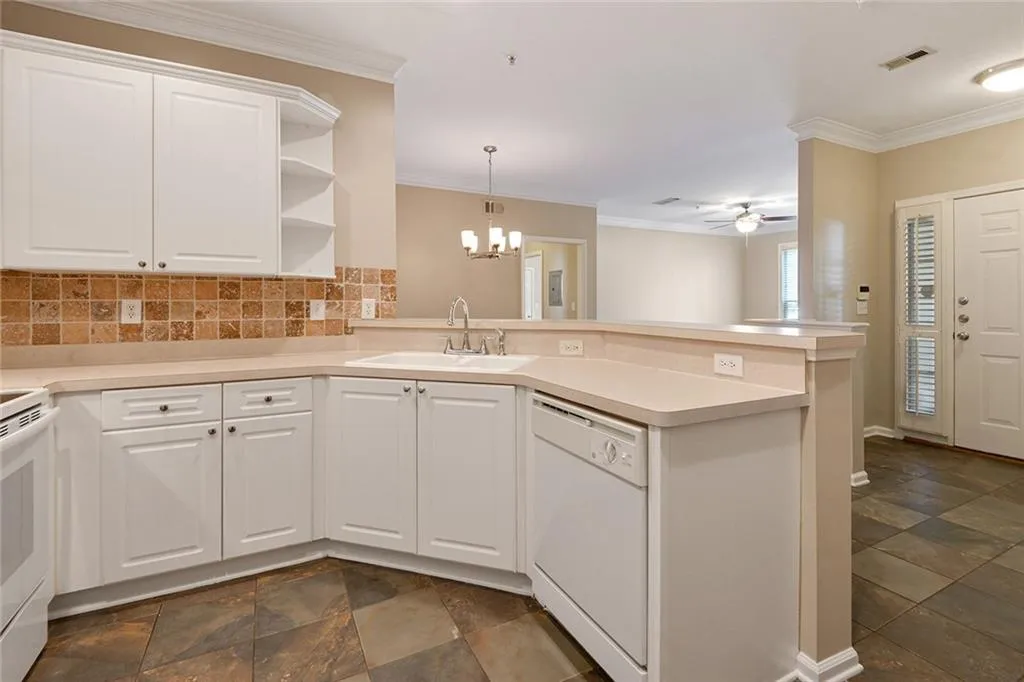 Kitchen featuring a peninsula, ornamental molding, white appliances, a ceiling fan, and white cabinets