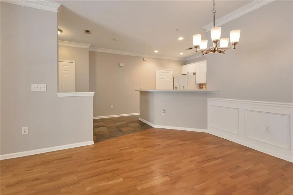 Empty room featuring crown molding, a chandelier, wood finished floors, and recessed lighting