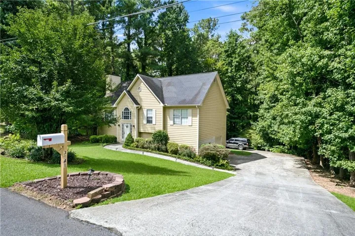 Yellow siding exterior with white trim, arched window above the entry, gabled roofline, and an extended driveway