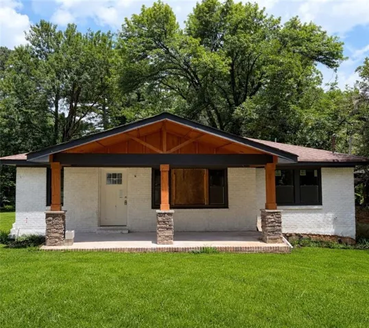 View of front of property with a front yard, a porch, and brick siding