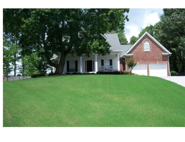 Home featuring a brick and white siding facade, a prominent front porch with columns, and a two-car garage