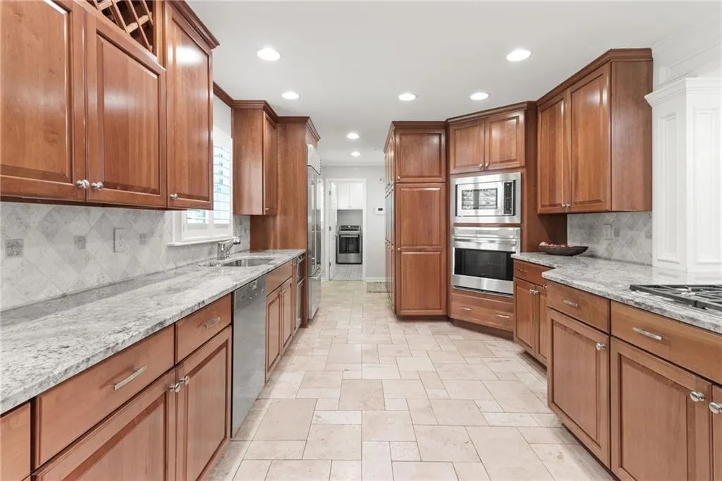 Rich cabinets with stone countertops and designer backsplash