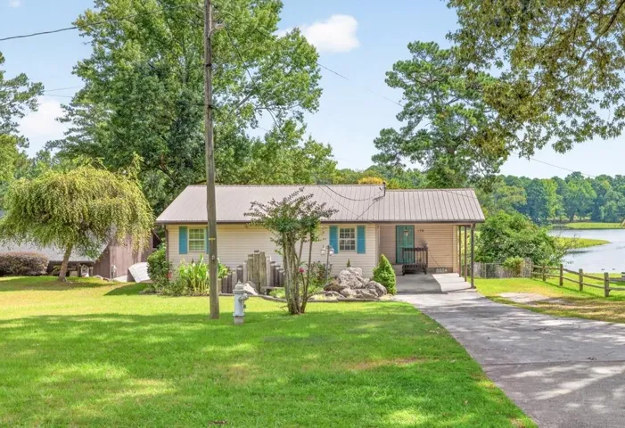Waterfront property featuring a metal roof, a covered porch, and a split-rail fence