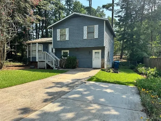 Split-level residence featuring blue siding, white trim, and a concrete driveway