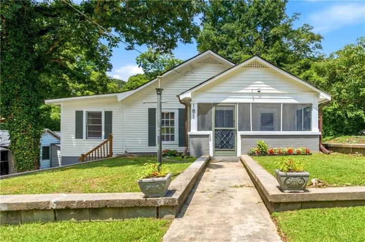 Charming white siding exterior with a screened front porch, dark green shutters, and a concrete walkway