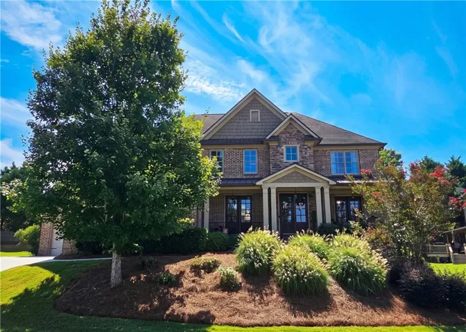 Brick and shake exterior with a covered entry, mature trees, and landscaped grounds