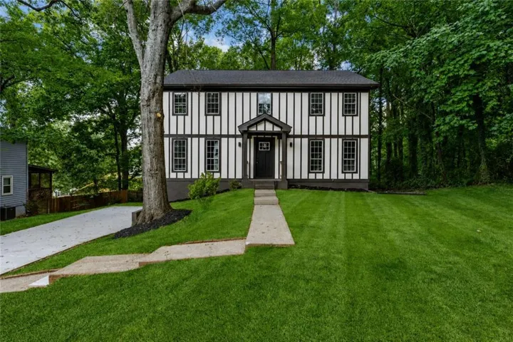 Tudor-style residence featuring a distinctive black and white exterior with vertical timber detailing and a gabled entryway