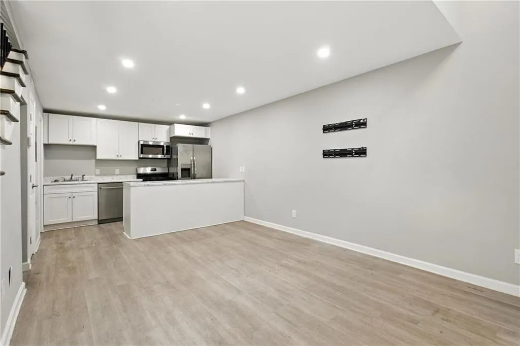 Kitchen with white cabinetry, appliances with stainless steel finishes, light wood-style floors, recessed lighting, and open floor plan