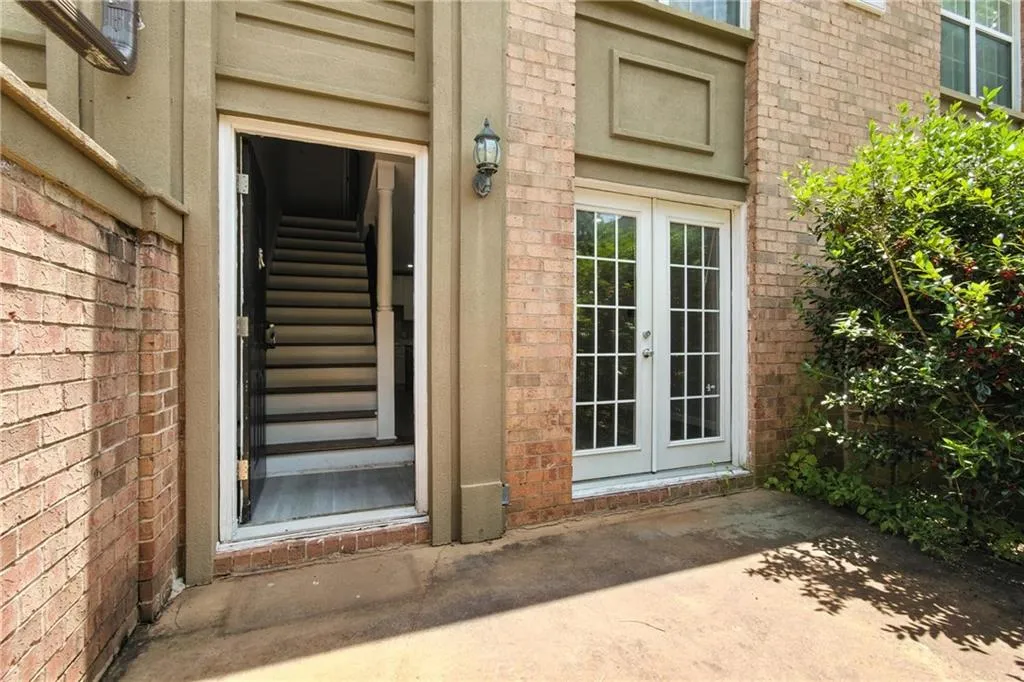 Doorway to property featuring brick siding, french doors, and a patio