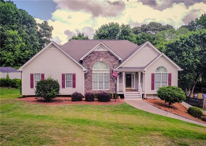 Exterior facade with stone accents and siding, arched window details, covered entry porch, and mature landscaping