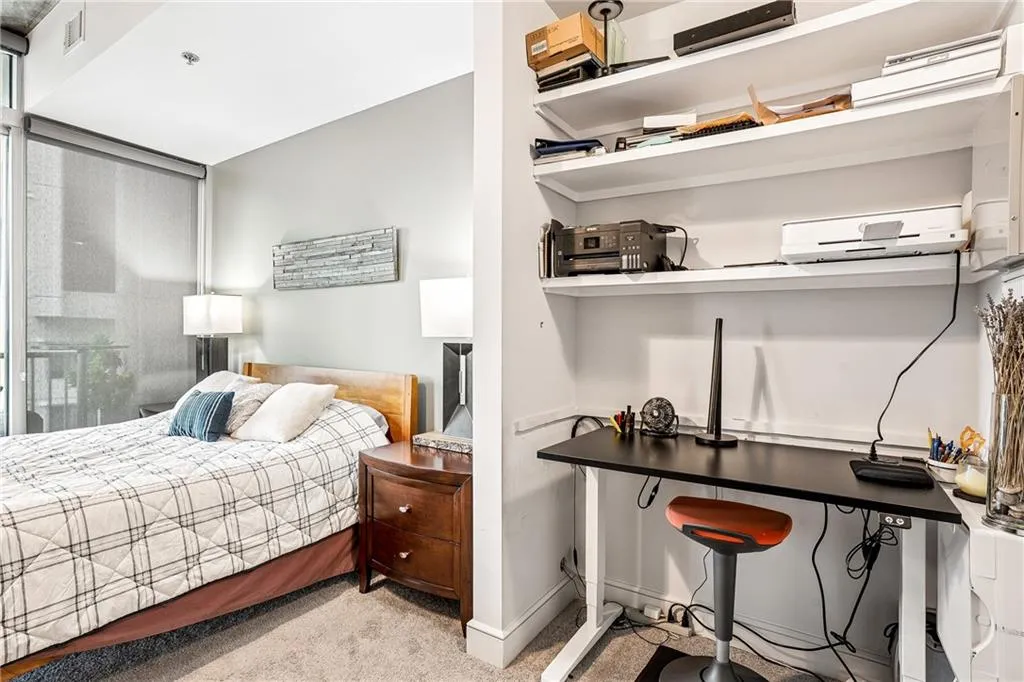 Bedroom featuring light colored carpet and a wall unit AC