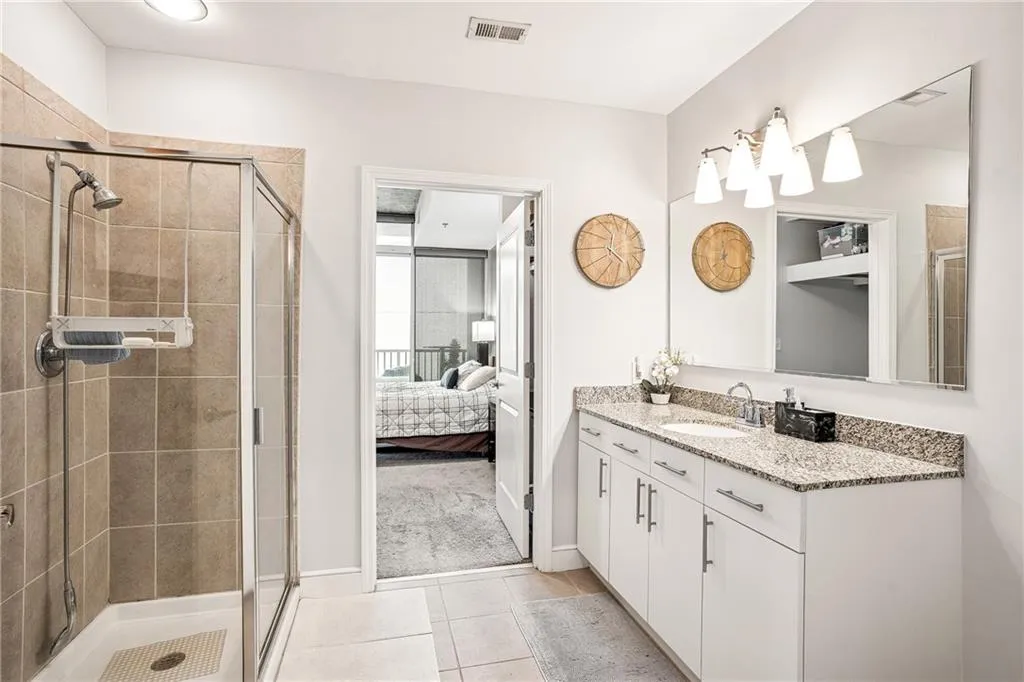 Ensuite bathroom featuring vanity, light tile patterned floors, and a stall shower