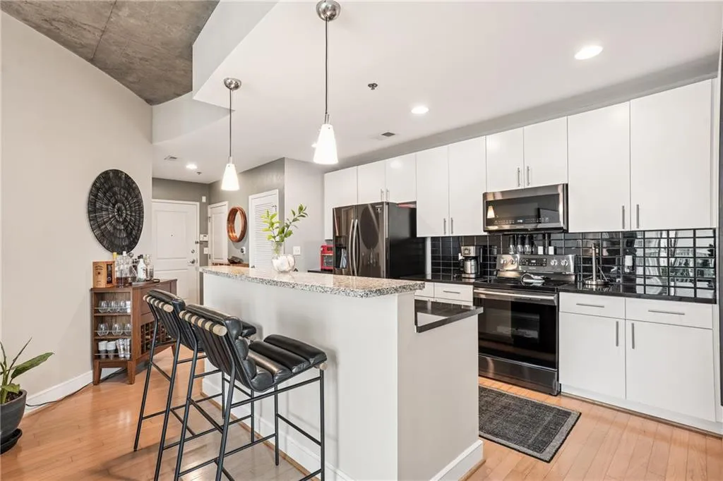 Kitchen featuring a kitchen bar, a center island, appliances with stainless steel finishes, decorative light fixtures, and light wood-style flooring
