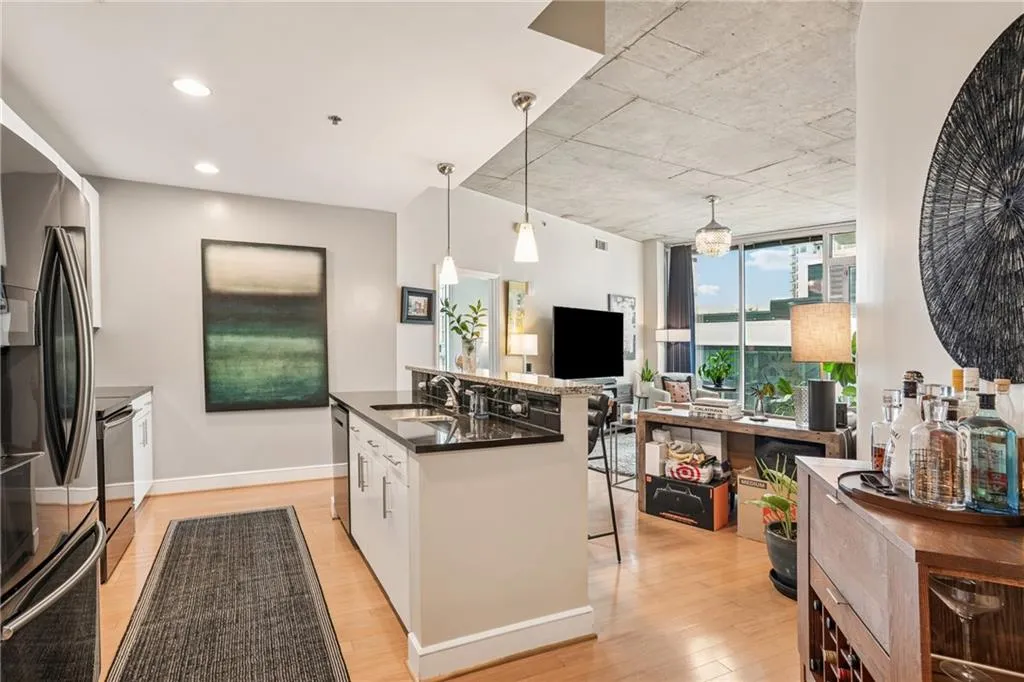 Kitchen featuring white cabinets, appliances with stainless steel finishes, pendant lighting, light wood-type flooring, and floor to ceiling windows