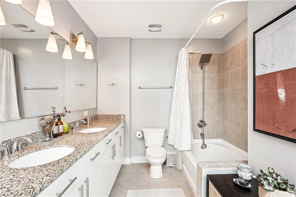 Full bath with shower / tub combo, double vanity, and light tile patterned floors