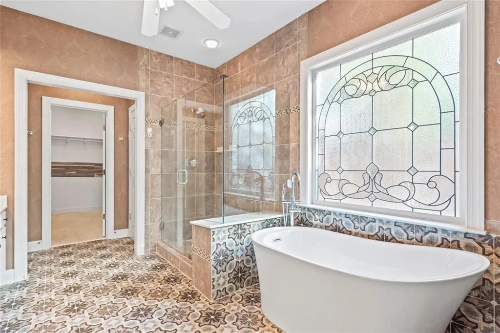 Frameless double shower & separate soaking tub accented by privacy leaded glass window