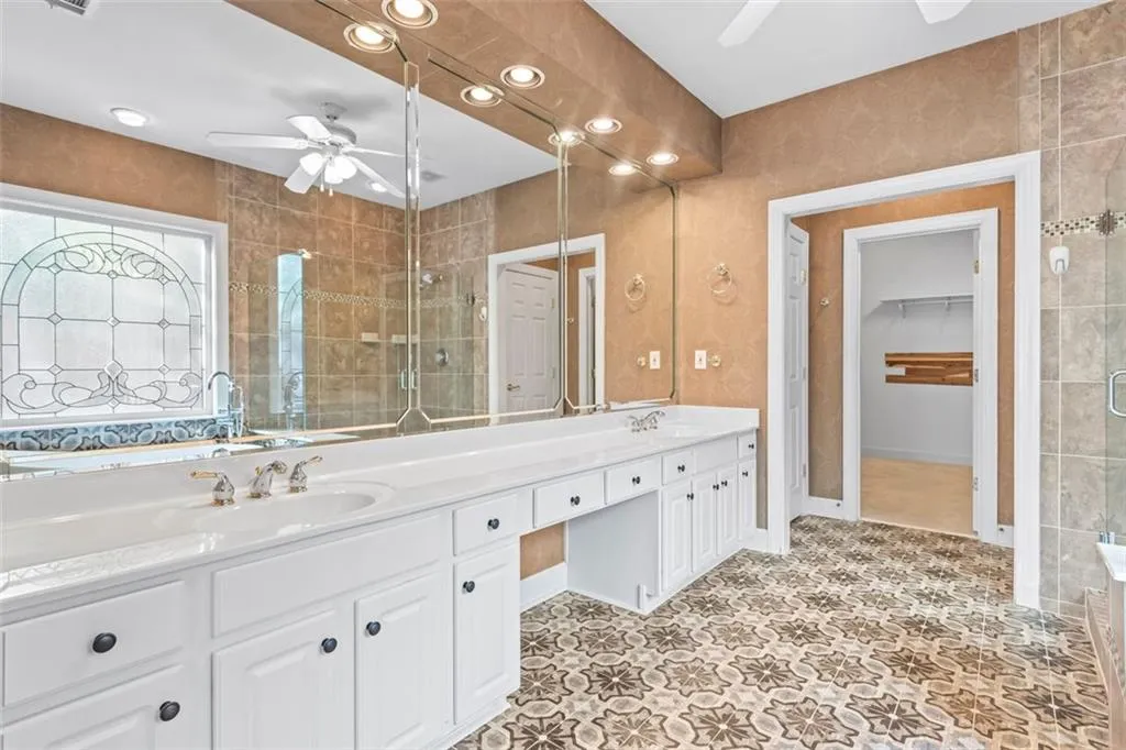 Updated primary bath has double vanities, beautiful floor tile and gorgeous window