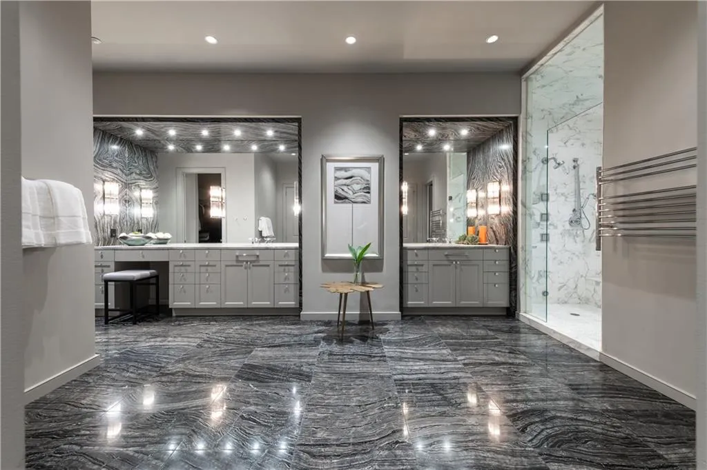 Primary bathroom featuring heated floors, towel warmer, walk-in steam shower, and dual vanities