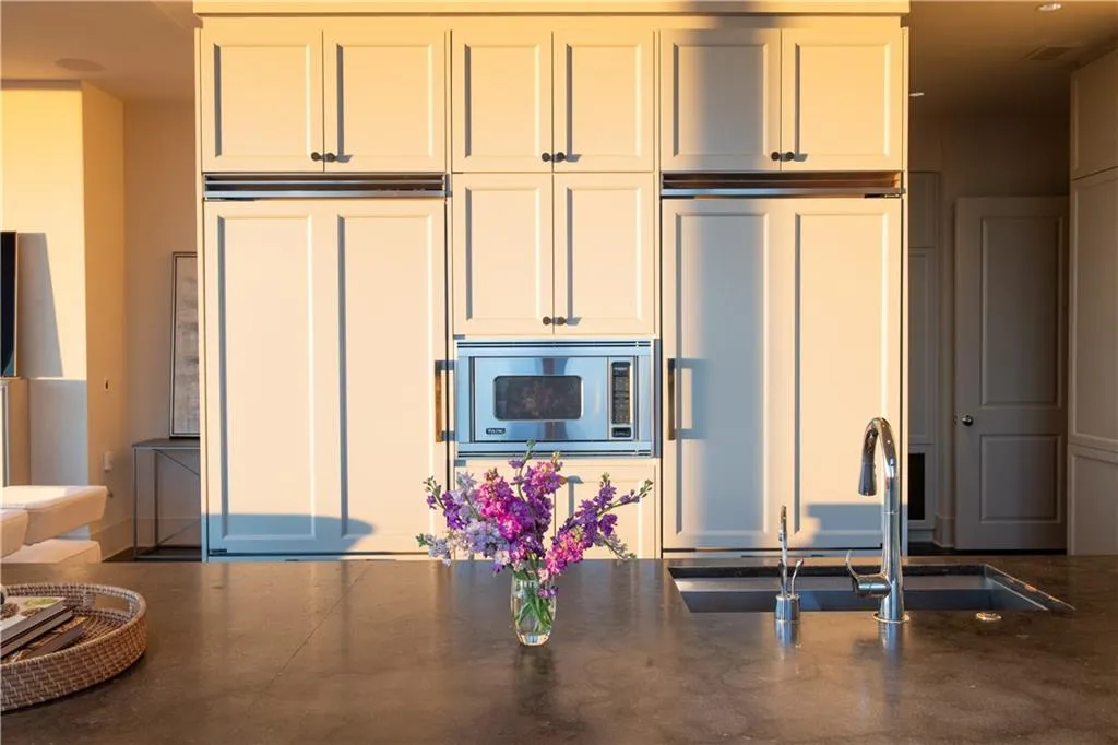 Kitchen with white cabinetry, sink, and built in appliances