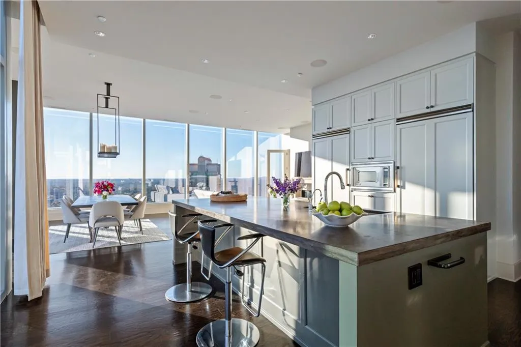 Kitchen featuring 2 Viking refrigerators, expansive windows, built in appliances, hardwood flooring, and a center island with sink
