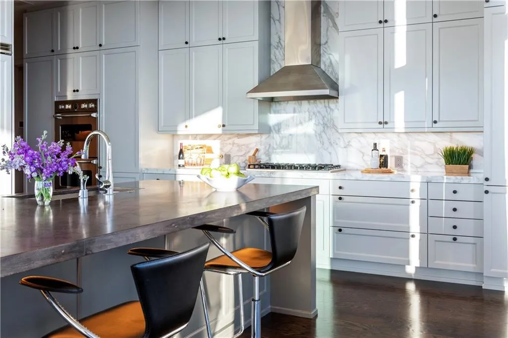 Kitchen with wall chimney range hood, sink, backsplash, stainless steel gas cooktop, and hardwood flooring