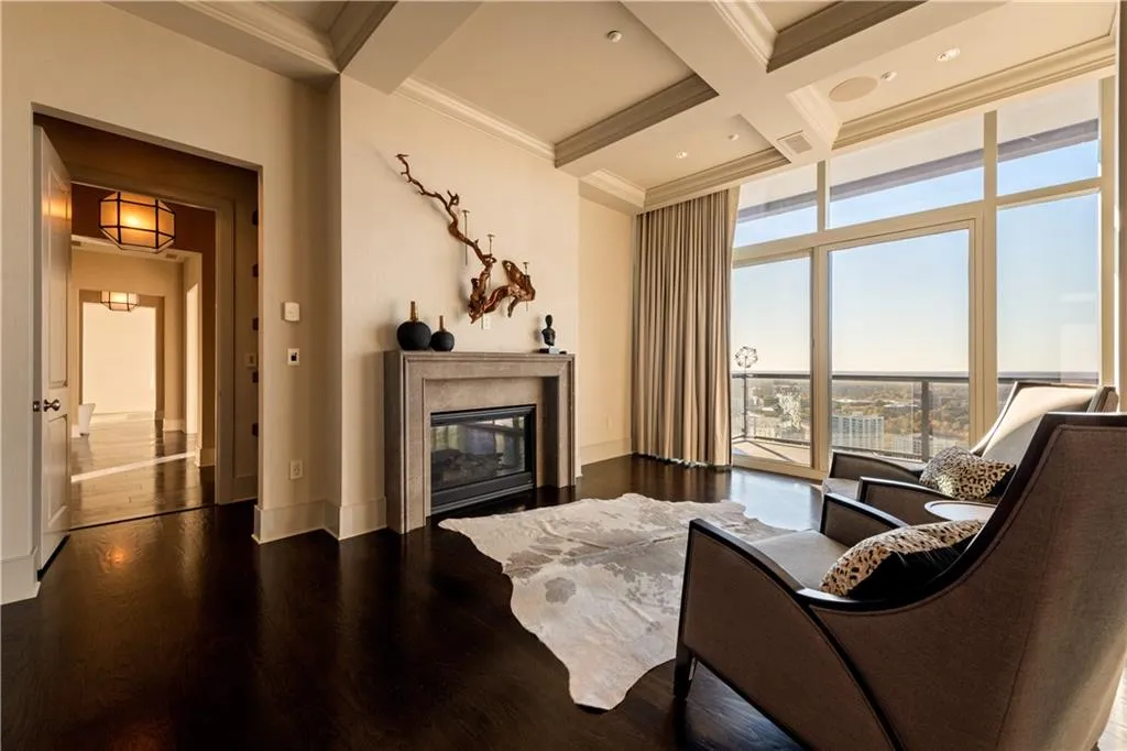 Primary bedroom seating area with beamed ceiling, ornamental molding, coffered ceiling, and hardwood floors