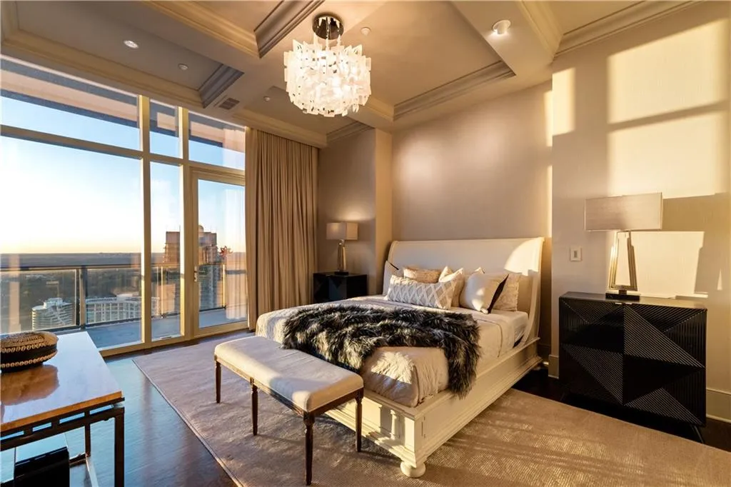 Sunset of primary bedroom with hardwood flooring, ornamental molding, coffered ceiling, with access to balcony, city view