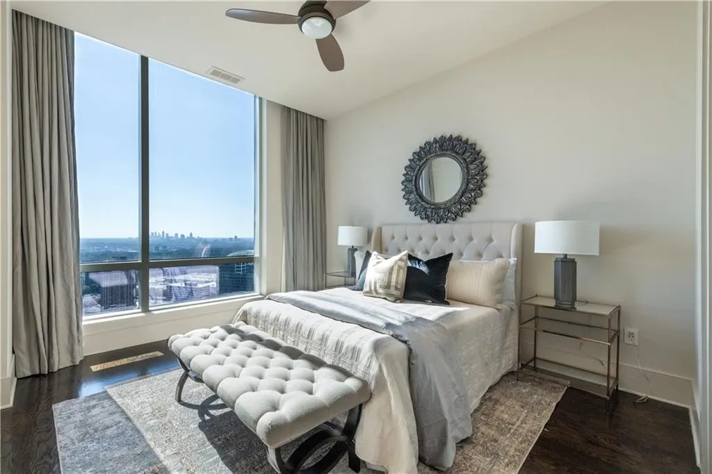 Bedroom with dark hardwood flooring, ceiling fan and views of the city