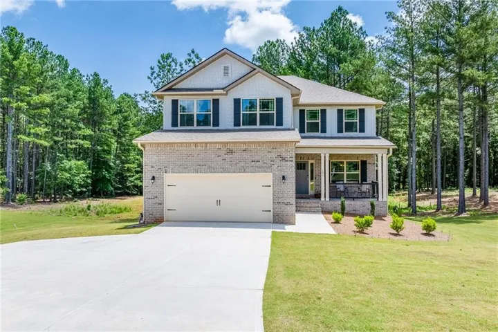Two-story residence featuring a brick and siding exterior, an integrated two-car garage, and a covered front porch