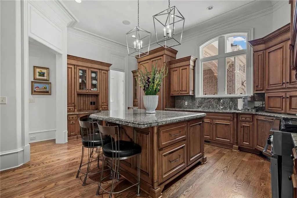 Kitchen featuring wood cabinetry, granite countertops, a central island, and wood-finish flooring