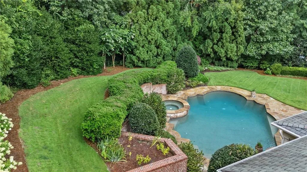 Landscaped yard featuring a freeform swimming pool, integrated spa, and flagstone coping