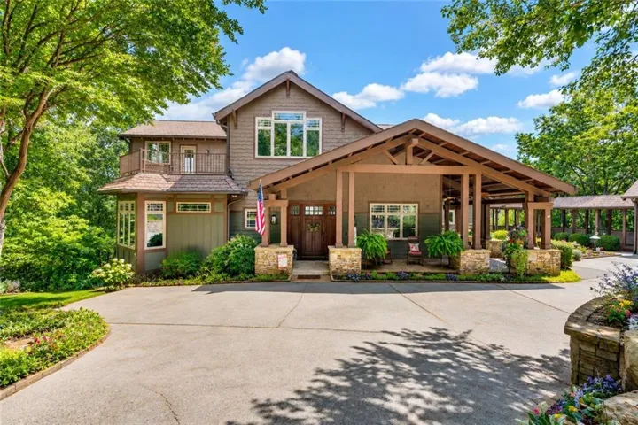 Craftsman-style residence featuring a prominent covered entry with exposed beam details, a multi-pane front door, and stone column accents