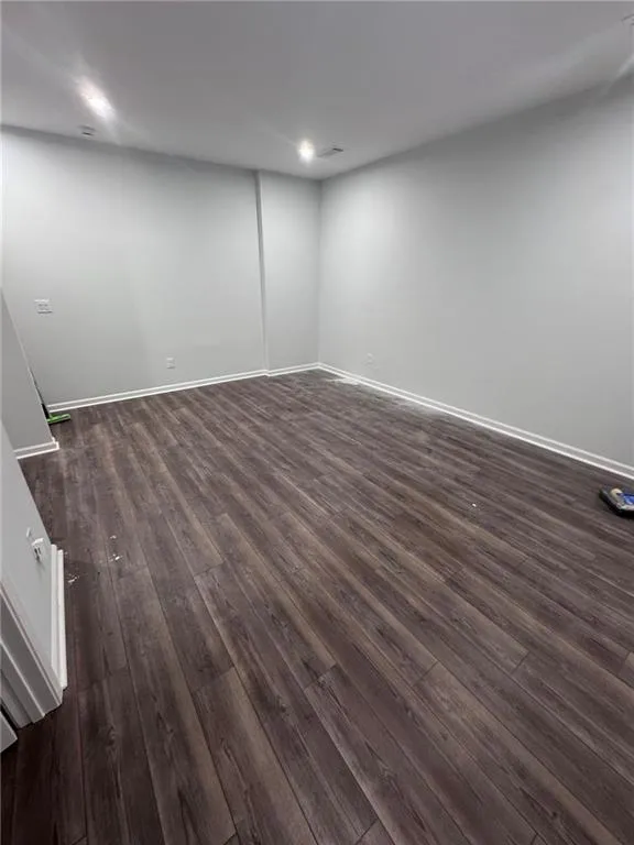 Spare room featuring dark wood-style floors